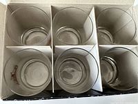 Top view of six drinking glasses in a divided box showing Glenfiddich logos inside bottoms of glasses