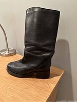Side view of left black leather winter dress boot highlighting leather texture and heel.