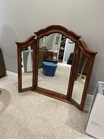 Photo of three-panel mirror with wood frame and arched top.