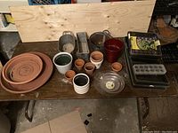 All items on a table showing terracotta pots, ceramic pots, metal base pots, seed trays, and greenhouse materials.
