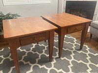 Pair of end tables positioned in front of fireplace on rug