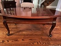 Full front view showing the smooth glossy oval tabletop and curved cabriole legs.