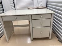 Solid wood white distressed desk with four drawers on one side and one drawer on the other side. Visible wear and distressing on finish.
