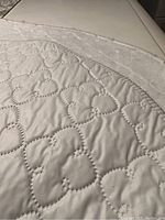 Close up of white quilted table pad with decorative stitched pattern.