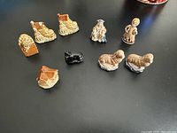 Photo of 9 Wade Red Rose Tea ceramic figurines depicting nursery rhyme characters and elements including two Old Women in a Shoe, two Sea Lions, Humpty Dumpty, Old King Cole, Wee Willie Winkie, Baa Baa Black Sheep, and House that Jack Built.