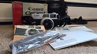Canon Canonet camera with original box, manual, carrying case, and strap.