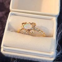 Front view of the vintage opal ring in a white ring box showing opal and decorative setting.