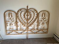 Full view of the rattan headboard showing its overall structure and ornate scroll design.