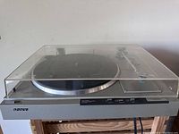 Side-view showing the turntable with lid closed, placed on wooden surface.