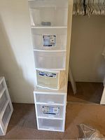 Stacked set of three Sterilite drawer storage units in white translucent plastic, two tall 3-drawer carts and one smaller 3-drawer unit, as seen in room corner.