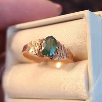 Close-up of the Victorian era ring with green oval stone set in rose gold colored setting.