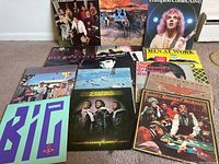 Photo showing all 15 vinyl LP record albums arranged on the floor, showing cover art including Billy Joel, 38 Special, Peter Frampton, Pat Benatar, AC/DC, Yes, Styx, Linda Ronstadt, Neil Diamond, and others.