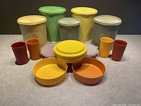 Top down and frontal view of all 22 vintage Tupperware pieces lined up to show assortment and colors.