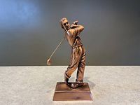 Front view of detailed bronze golfer sculpture captured mid-swing on a rectangular base