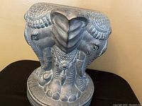 Front and side view of ceramic elephant plant stand showing three elephants with detailed carved patterns and antique finish.