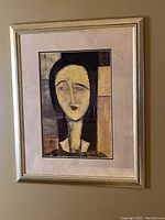 Framed Colette art print by Guy Mourand, showing abstract female portrait and silver frame on a wall.