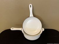 Front angle showing the white enamel sauce pot and lid inside the pot, clear view of handles and enamel interior.