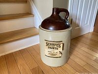 Full view of front of large Medalta crock jug with Scarfe's Paints orange shellac label