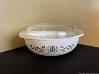 Overall view of Pyrex round casserole dish with lid on a black surface against a beige wall