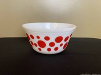 Front angled view showing the bowl's flared rim and red polka dot pattern on white milk glass.