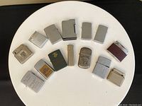 All 14 lighters arranged in a semicircle showing variation in brand, color, and condition.
