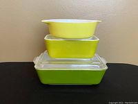 Stack of three Pyrex dishes showing the verde green color and white interior.