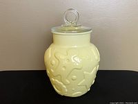 Full view of the yellow gingerbread star cookie jar with the clear round handle lid on top.