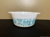 Front view showing the turquoise Butterprint design on white glass casserole dish with handles.