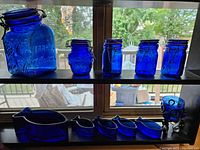 Overview of cobalt blue jars and fish-shaped bowls on shelves near window.