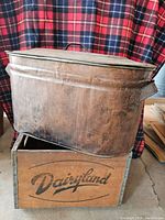 Vintage copper oval boiler on top of Dairyland wooden milk crate against a flannel backdrop