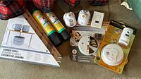 Photo of three boxed new corner shelves, two rolled shelf liners and four smoke/fire safety alarms including a Kidde smoke alarm and Universal 4-in-1 alarm in packaging