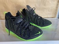 Side view of pair of black Nike Air running shoes with neon green sole and accents, showing knit upper and laces.