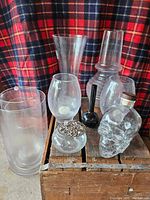 Group shot of all glass vases, skull bottle, potpourri dish, and candle holders showing variety of shapes and sizes against plaid background.