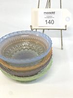 Stacked view of four Anchor Hocking Wexford pastel pressed glass fruit bowls showing scalloped edges and textured patterning.