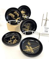Photo of five black lacquer bowls each with unique traditional Japanese gold motifs including pine, chrysanthemum, bamboo, wisteria, and flowering willow designs.