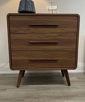 Front view of walnut finish dresser with three drawers and angled legs