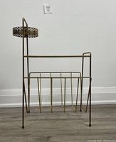 Full view of the brass magazine rack showing the ashtray holder on one side and the magazine storage compartment with vertical brass rods.