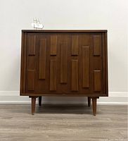 Front view showing geometric relief panels and tapered legs