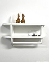 Front view of vintage painted white wood hand towel rack with shelf, showing the straight horizontal shelves and cylindrical towel bar underneath.