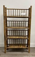 Front view of the antique folding bamboo shelf showing all four tiers and drop-down mechanism with sides folded out.