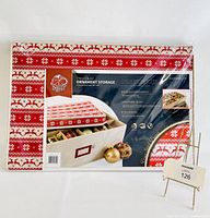 Front view of the new packaging showing the box with red and white Christmas pattern on lid and partial image of ornaments inside.