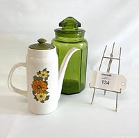 Wide photo of the vintage Aynsley coffee pot with floral design and avocado green LE Smith glass canister alongside metal stand with auction tag