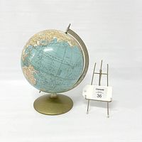 Full view of vintage globe on circular metal base with a nearby display stand for reference.