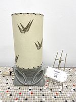 Front view of vintage TV lamp with grey ceramic base and tan patterned fiberglass shade showing whipstitch trim and abstract pattern.