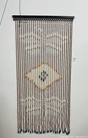 Full view of the wood beaded curtain hanging against a white wall, showing the overall pattern and size.