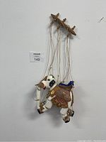 Front view of the white wooden elephant marionette hanging on wall with control bar and strings visible