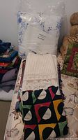 Blue and white floral comforter still in packaging with other folded throws and bedding items underneath.