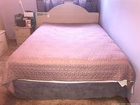 Full view of bedframe with mattress and bedding covering it
