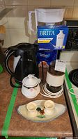 Overview of all items including Brita pitcher and filters, electric kettle, electric grinder, sugar bowl, egg cups, mini platter, and Tetley tea box