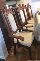 Side angle showing three regular pressback dining chairs and one armchair, all upholstered with carved wooden frames.